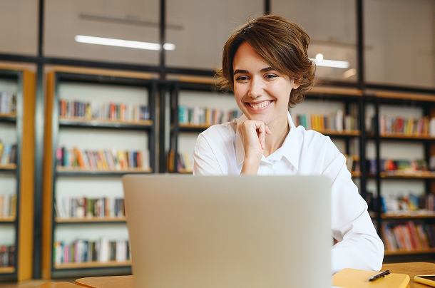 a smiling woman looking at a laptop screen